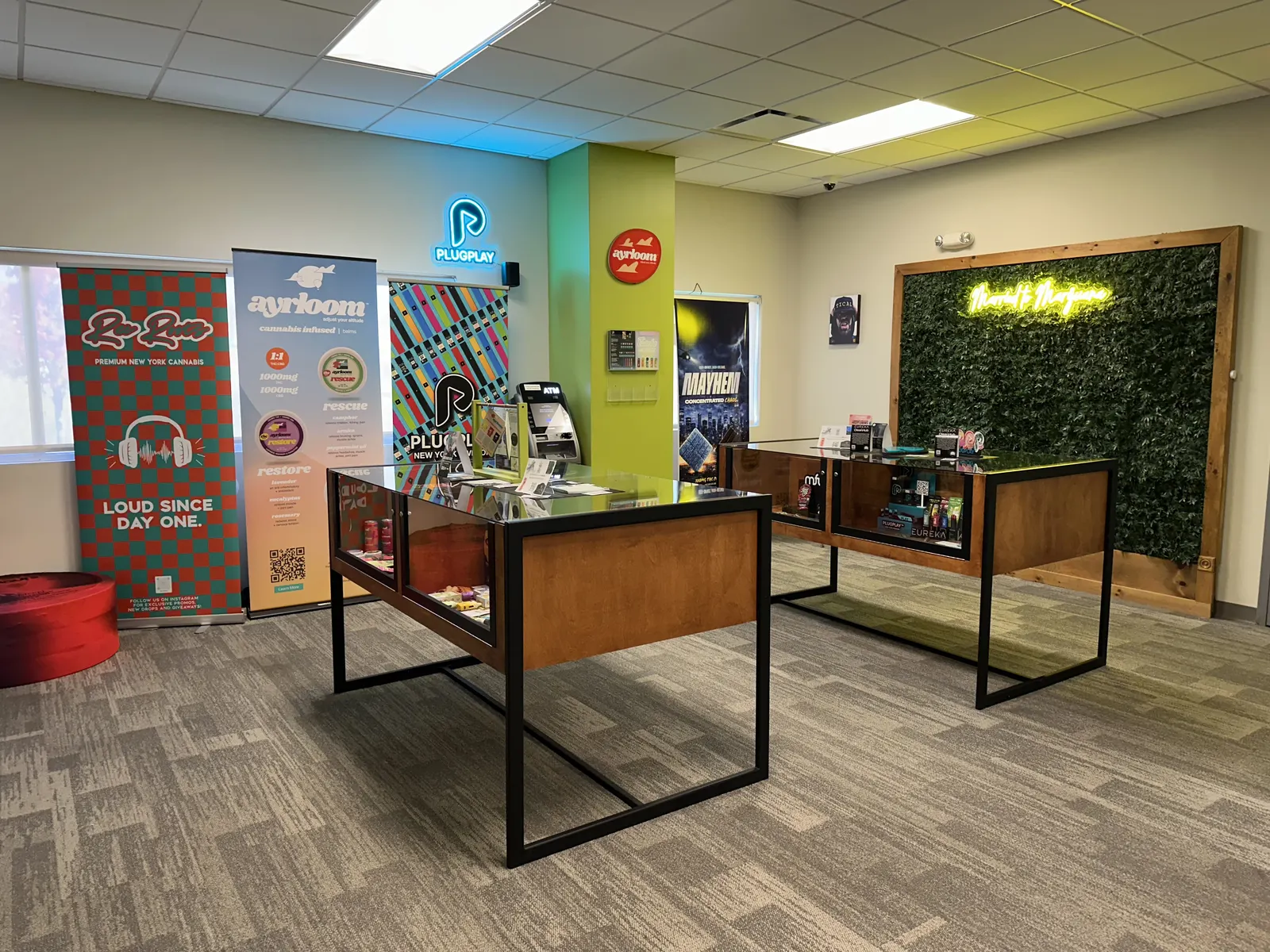 The Amsterdam Cannabis sales floor with timber display cases and a green pillar